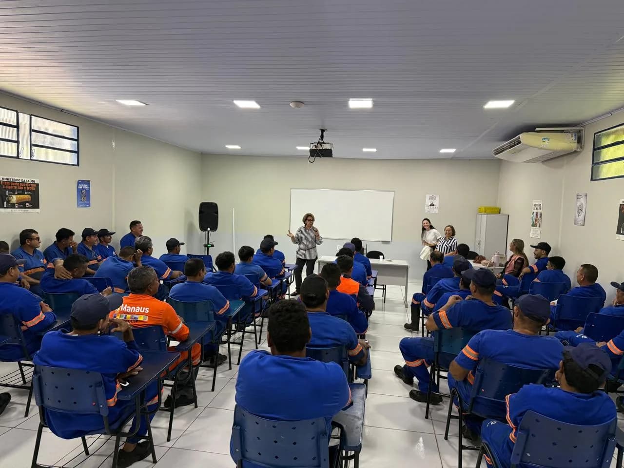 Equipe operacional reunida em auditório durante palestra de saúde emocional conduzida pela Priorize